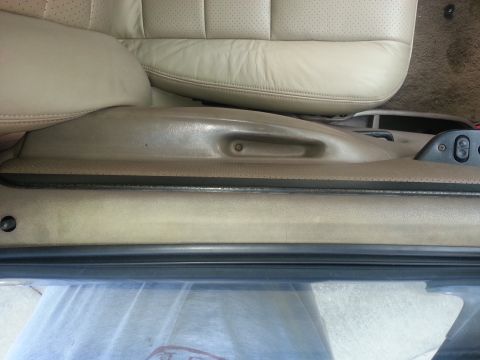 1994 Ford Bronco - Close-up of a car's interior seat trim, showing tan leather and plastic components.