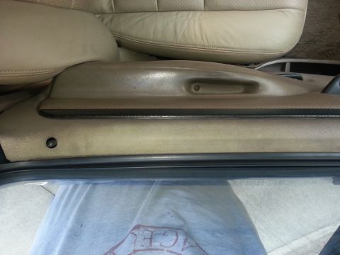 1994 Ford Bronco - Close-up view of the interior door panel and tan leather seat, showing the armrest and stitching details.
