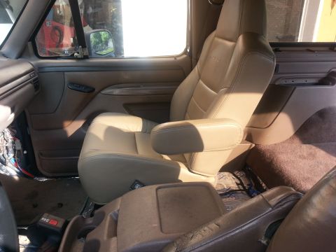 1994 Ford Bronco - Interior view of the vehicle's front seats, showing tan leather upholstery and the center console area.