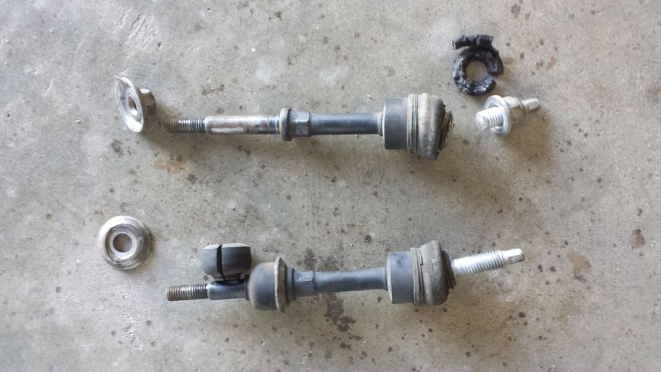 two stabilizer bar links and some hardware on a concrete surface
