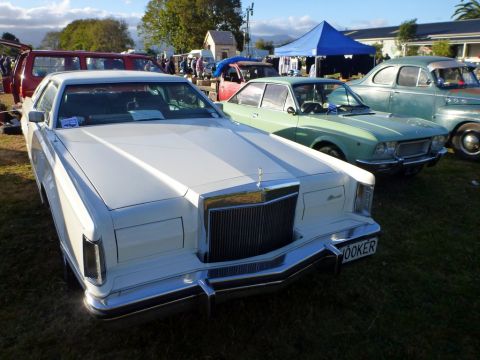1969 Lincoln Continental - A white Lincoln Continental is parked at an outdoor event, with other vehicles visible in the background.