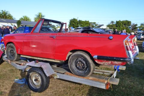 1969 Lincoln Continental - A red convertible is loaded onto a trailer, showing its side profile and a folded black soft top.