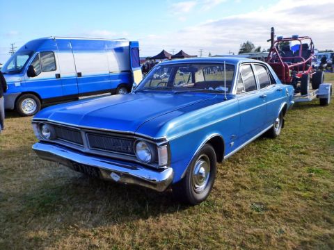 1969 Lincoln Continental - A blue 1969 Ford Falcon sedan is seen at an outdoor event, towing a trailer with a red buggy.