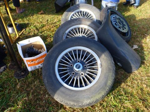 1969 Lincoln Continental - A collection of car wheels and a fender are displayed on the grass, with a box of automotive parts nearby.