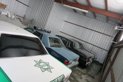 1991 Ford LTD Crown Victoria - Several police vehicles are lined up inside a storage building.