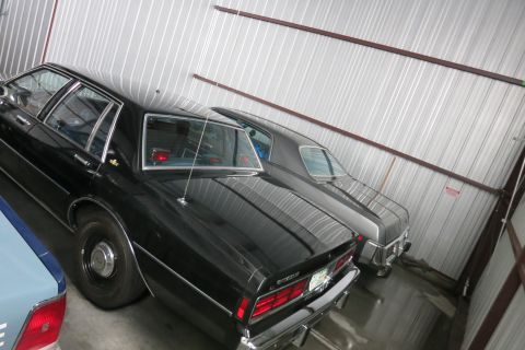 1991 Ford LTD Crown Victoria - Two sedans are parked side-by-side in a storage unit.