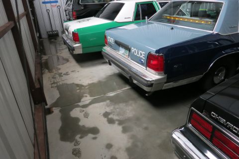 1991 Ford LTD Crown Victoria - A rear view of a 1991 Ford Crown Victoria LTD police car, part of a collection in a garage.