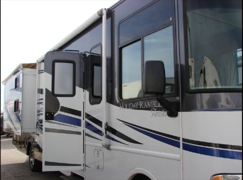 2010 Ford F-450 - A motorhome is parked next to another vehicle, showing its side with an open door and decorative stripes.