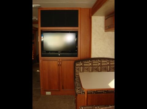 2010 Ford F-450 - RV interior features a TV, cabinets, and dinette seating.