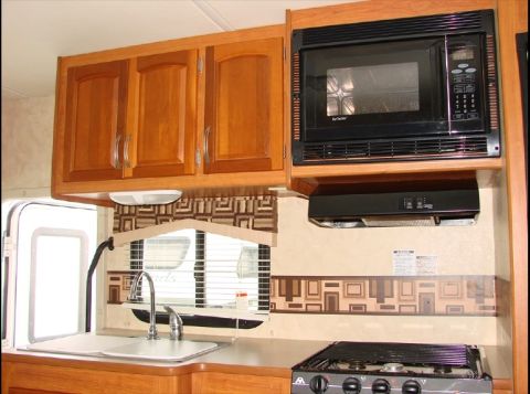 2010 Ford F-450 - Interior view of an RV kitchen, showing cabinetry, appliances, and sink area. A watermark is present on the lower right.