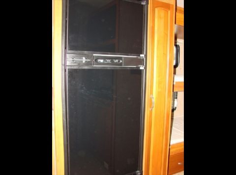 2010 Ford F-450 - Interior view of a black refrigerator with a digital control panel, set within a wooden cabinet.