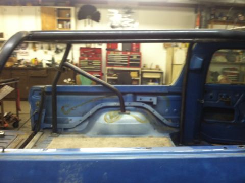 1979 Ford Bronco - The interior of a blue 1979 Ford Bronco shows a custom roll cage installed in the rear cargo area.