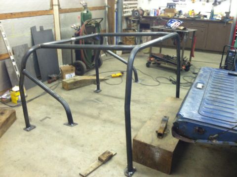 1979 Ford Bronco - Workshop scene with a newly fabricated roll cage and a blue vehicle tailgate.