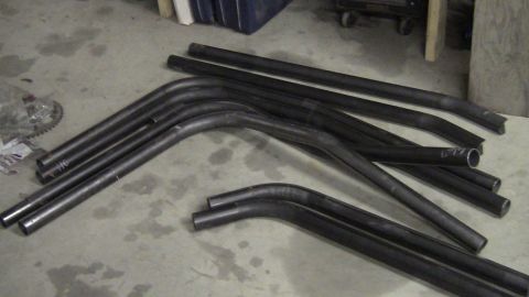 1979 Ford Bronco - Various metal tubes are laid out on a workshop floor, some with distinct bends.