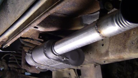 1979 Ford Bronco - The underside of a vehicle reveals a rusty frame and a section of the exhaust system.