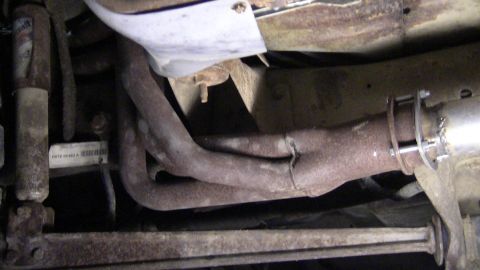 1979 Ford Bronco - Underside view of rusty exhaust manifold and pipes, with a visible part number label.