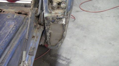 1979 Ford Bronco - Close-up of a heavily rusted blue tailgate hinge area, revealing damaged metal and exposed components.