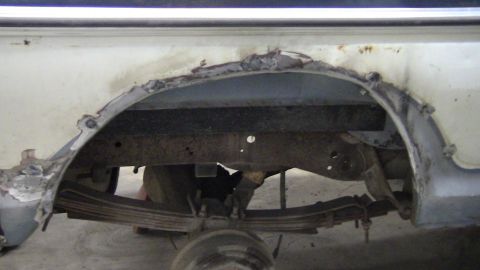 1979 Ford Bronco - The rear wheel well and suspension components show extensive rust and damage, indicating a need for repair.