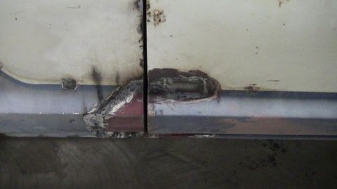 1979 Ford Bronco - Detail of corrosion and welding on a vehicle's body panel.