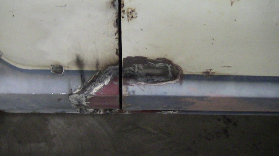 Close-up of a rusted and repaired metal panel, possibly a vehicle door or body section