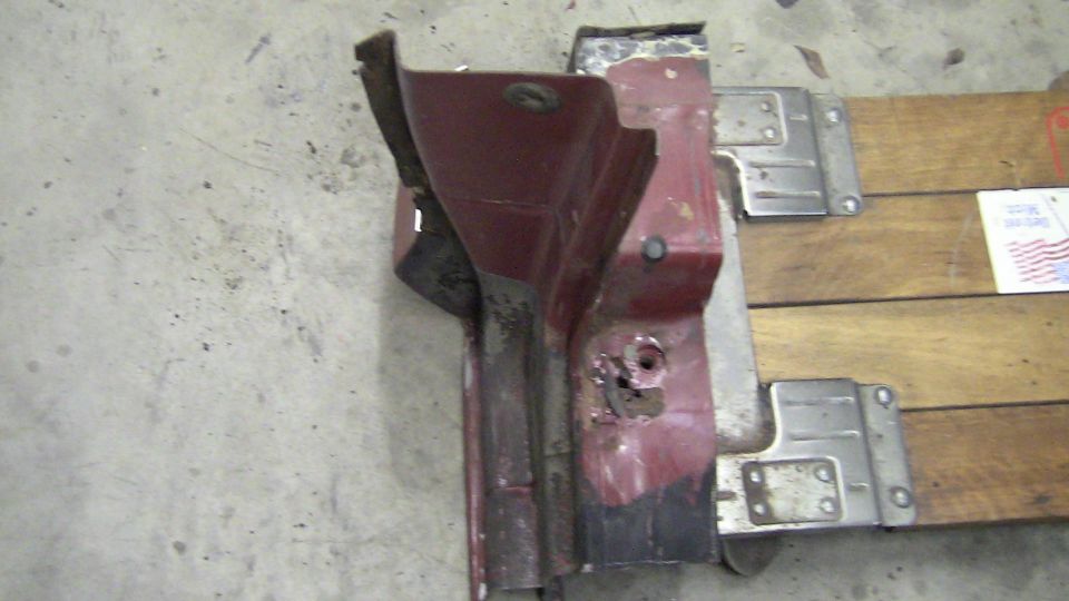 Red metal car part with rust and mounting brackets