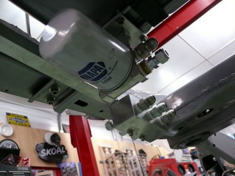 NAPA oil filter with fuel lines attached to a metal bracket, mounted under a vehicle