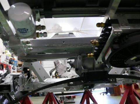 Underside of a car on jack stands, showing suspension and oil filter