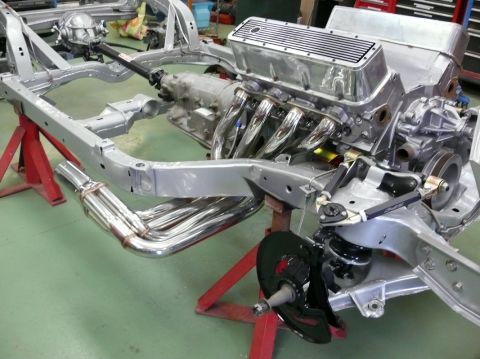 Corvette chassis with engine and chrome headers on red stands