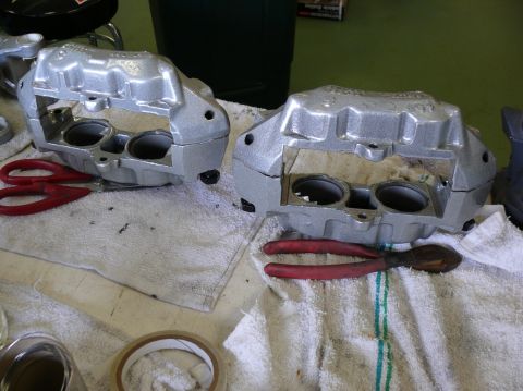 Pair of silver brake calipers with red-handled pliers and scissors