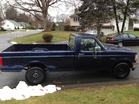 2004 Ford Crown Victoria - This dark blue pickup truck, identified by an F-150 badge, is parked on a residential street.