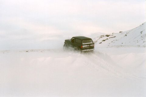 1996 Ford Bronco - Black 1996 Ford Bronco navigates a snow-covered landscape, rear view.
