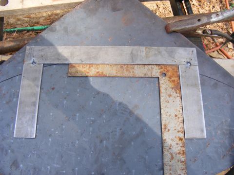 Metal plate with two metal squares and a ruler on it, showing some rust and wear