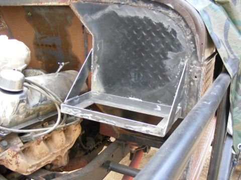 Custom metal bracket welded onto engine bay, showing engine parts and diamond plate