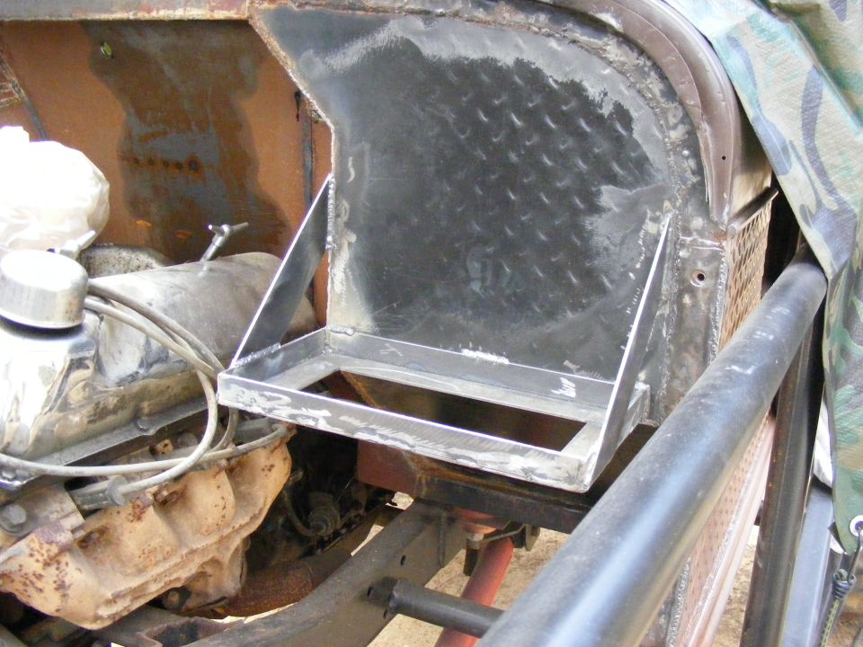 Custom metal bracket welded onto engine bay, showing engine parts and diamond plate