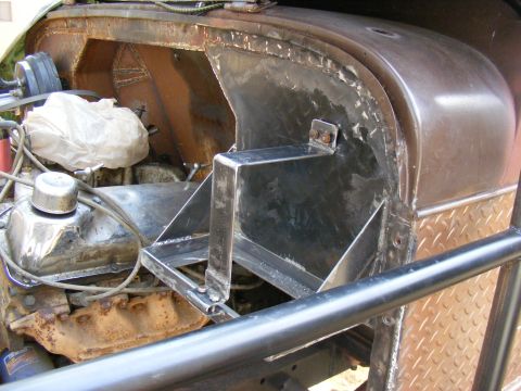 Custom metal fabrication in engine bay, showing engine parts and roll cage tubing