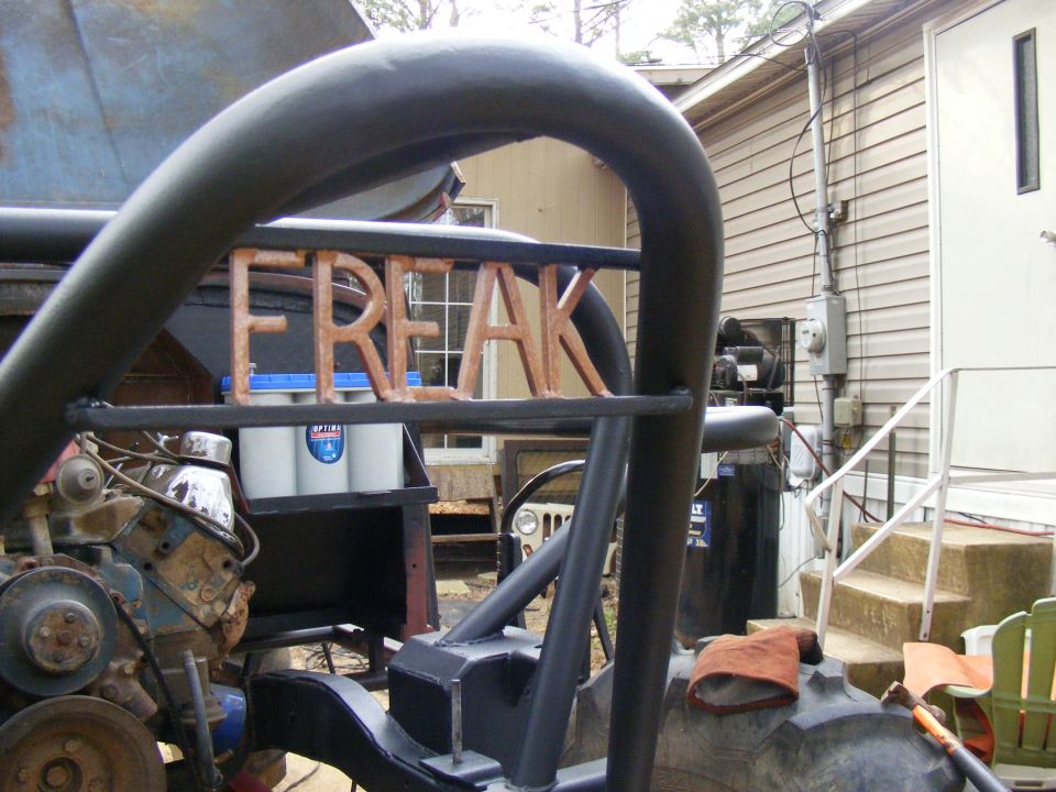 Custom off-road vehicle with 'FREAK' spelled out on the roll cage. Engine is visible