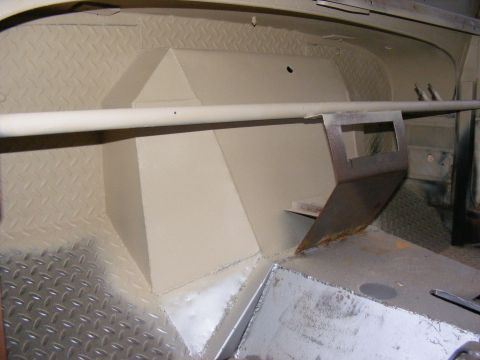Interior of a vehicle showing diamond plate flooring and painted metal panels. A metal bar runs horizontally a