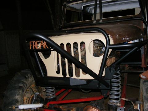 Custom off-road vehicle front grille with "FREAK" text, large tires, and roll cage