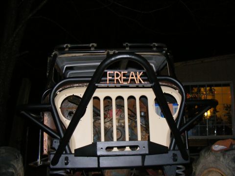 Modified Jeep with "FREAK" lettering on the grille guard, custom bumper, and visible engine