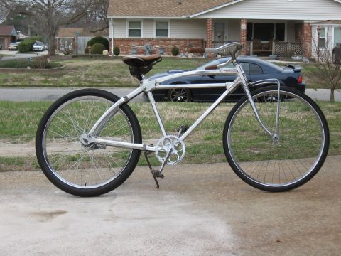 Custom chrome bicycle with brown leather seat and large wheels parked on concrete