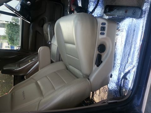 1994 Ford Bronco - The interior of a vehicle is shown, tan leather seats and the steering wheel. The floor is covered with insulation material.
