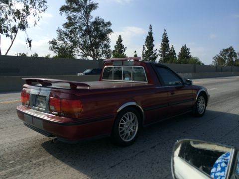 1968 Ford Mustang - A red pickup truck with a spoiler and chrome trim is seen from the rear on a highway.