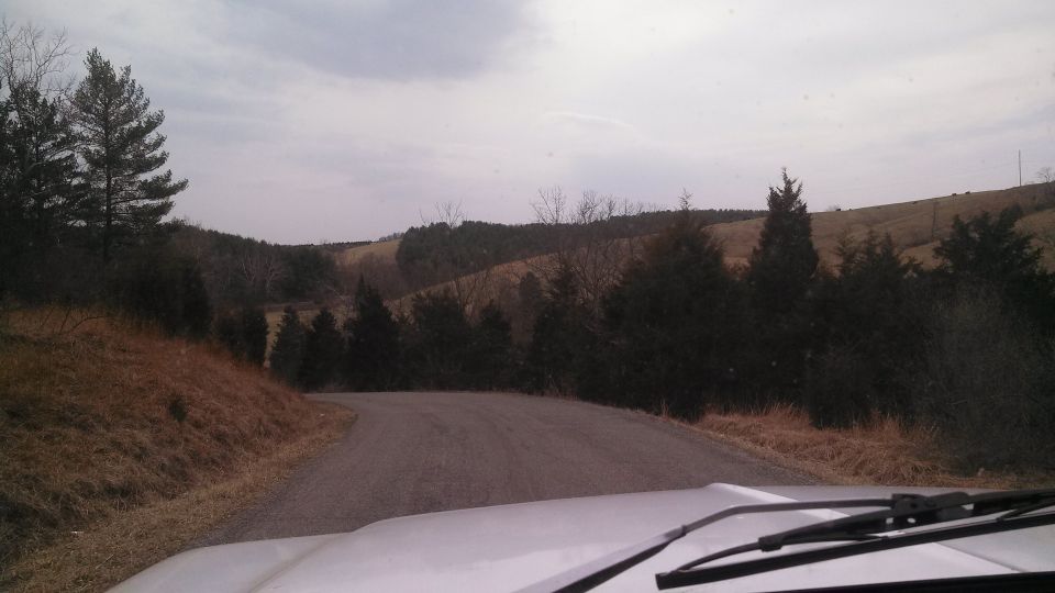 White dashboard and windshield wipers in foreground, rural road ahead