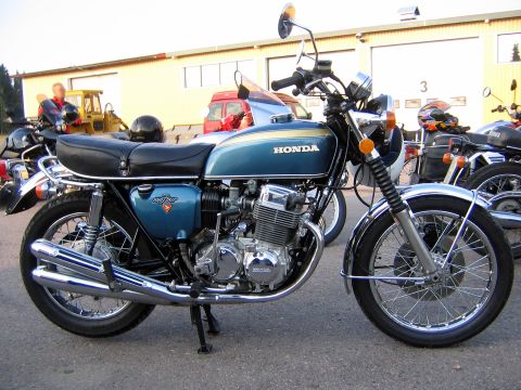 1960 Ford Falcon - A blue Honda motorcycle is parked next to other vehicles outside a building.