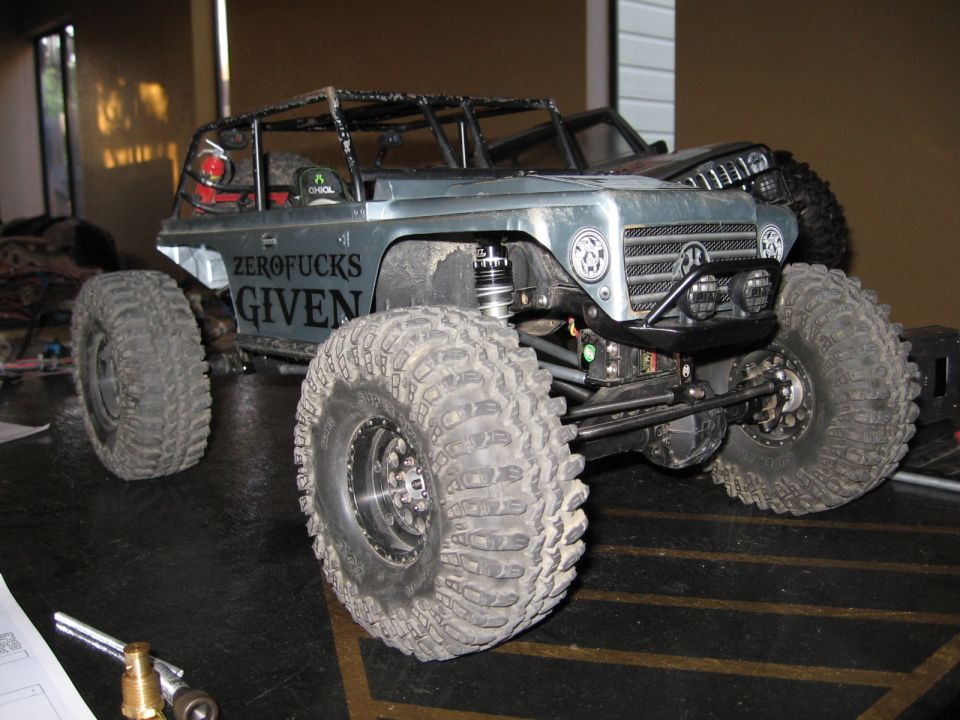 RC rock crawler with 'ZERO FUCKS GIVEN' on the side, another RC vehicle behind it