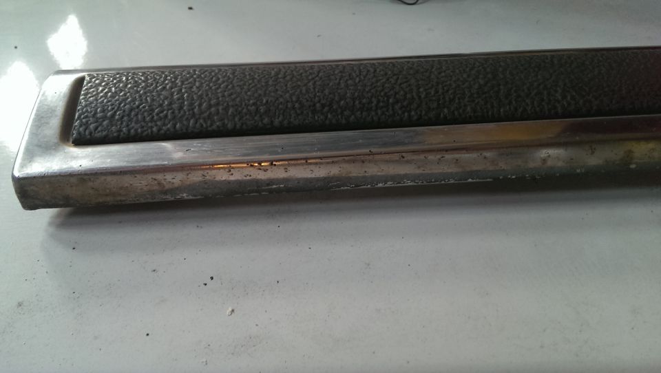 Chrome trim piece with black textured insert, showing wear and some rust spots