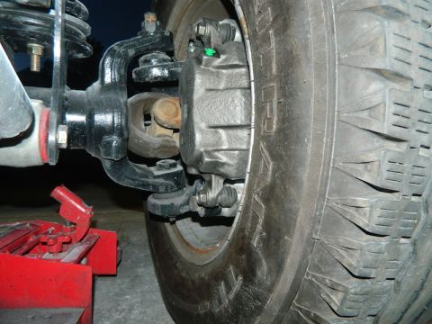 1979 Ford Bronco - The image shows a close-up of a vehicle's brake caliper, rotor, and tire, with a red jack visible in the lower left corner.