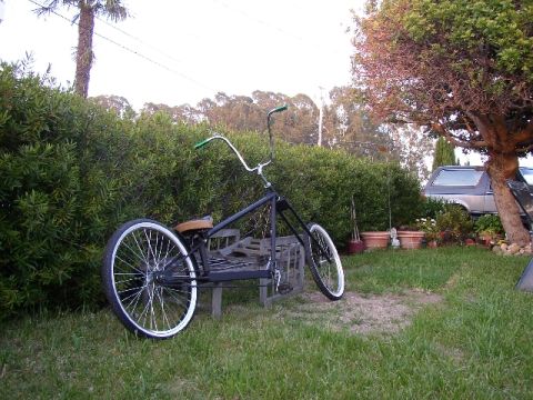 1989 Ford Bronco - A custom chopper bicycle is parked outdoors next to a silver SUV.