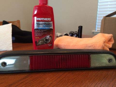 1995 Ford Bronco - Car tail light assembly and cleaning supplies are laid out on a wooden table.