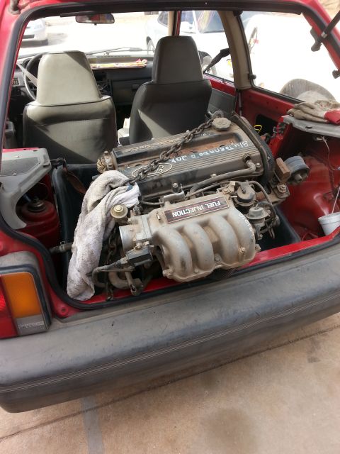 1991 Ford Festiva - Engine is loaded into the rear of a red 1991 Ford Festiva.